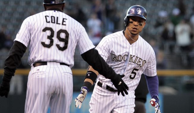 Colorado Rockies third base coach Stu Cole (39) congratulates Rockies&#x27; Carlos Gonzalez (5) after Gonzalez&#x27;s home run in the first inning of a baseball game against the New York Mets in Denver, Thursday, May 1, 2014.(AP Photo/Joe Mahoney)