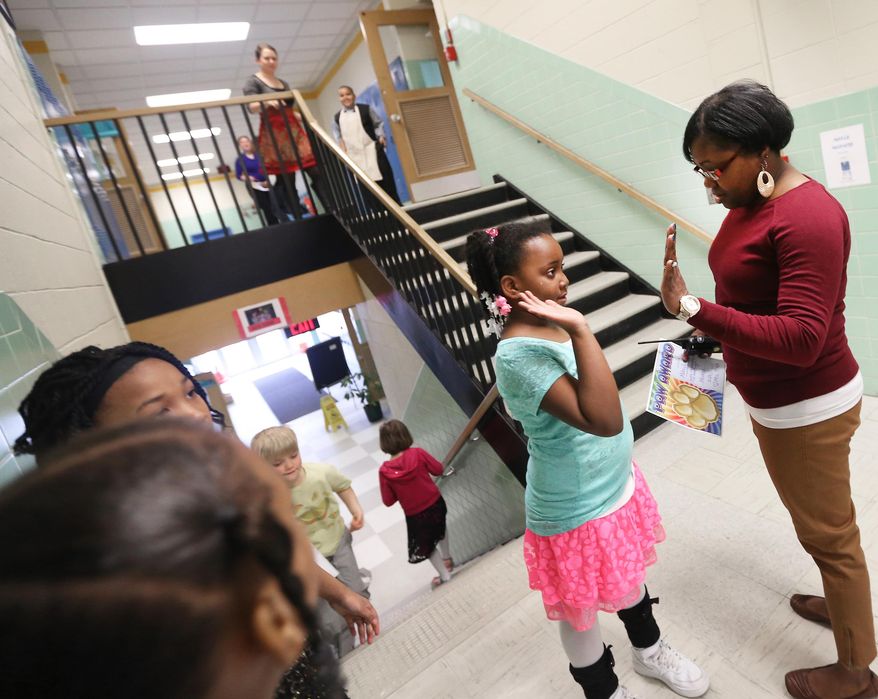 Mendota Elementary School parent liaison Sonia Spencer congratulates a student's recent achievement while crossing paths with the youngster in the hallways of the Madison, Wis. school Friday, March 28, 2014. The Madison School District is opening its schools to students' parents as a way to engage families. (AP Photo/Wisconsin State Journal, John Hart)