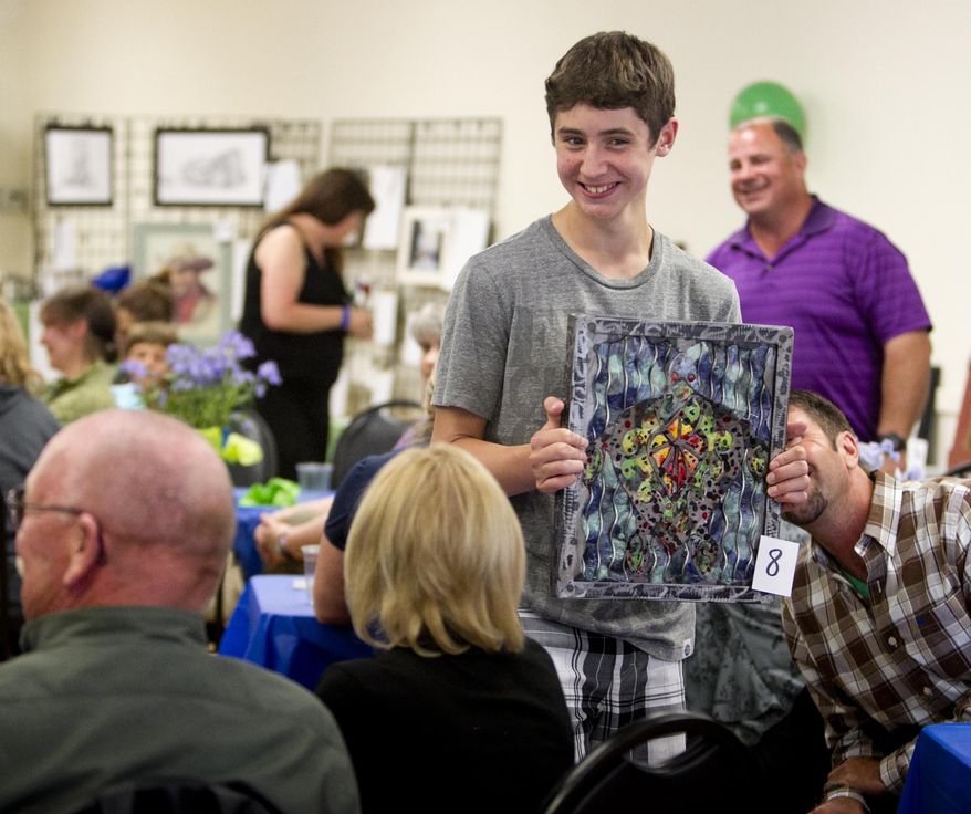 ADVANCED FOR RELEASE SATURDAY, MAY 3, 2014 Anthony Morales, 14, carries an art piece up for auction as potential buyers get a better view during the bidding Friday April 25, 2014 in New Plymouth, Idaho. The auction raises money for the Robert Manwill Scholarship Fund benefiting Manwill's lassmates when they graduate from high school in 2017. (AP Photo/The Idaho Statesman, Darin Oswald)