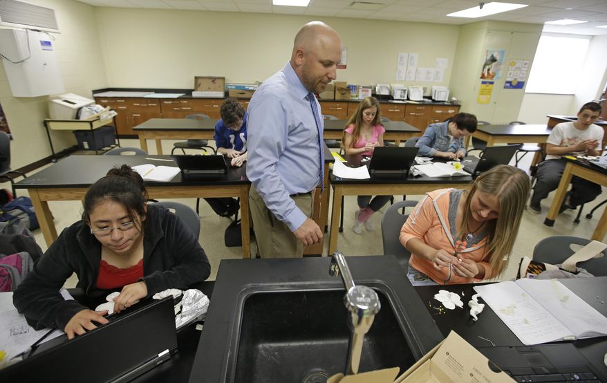 Beech Grove High School teacher Chris Kaufman watches as Rebecca Goodman, right, makes a flower out of clay during a Plant and Soil Science class Wednesday, April 30, 2014, in Indianapolis. High school agriculture programs sprouting across the nation’s Corn Belt are teaching teenagers, many of them in urban environments, that careers in the field often have nothing to do with cows and plows. (AP Photo/Darron Cummings)