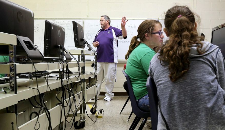 Elba Public School teacher Mike Miller, center, teaches a computing class to middle school students, including eighth-grader Devanee Spilinek, second from right, on May 1, 2014. Elba Public School has an average daily enrollment of 25 or fewer students in ninth through 12th grades. Next year, it is on track to stay that way. Because of a state law, however, that means the school might be forced to close its doors. Superintendent Mikal Shalikow and the school board are searching for options, from bringing in students to unifying or even consolidating with another school. But while Elba's issue is a question of how to keep its school open, as in many small towns, it is also a question of whether the community will survive. (AP Photo/The Independent, Barrett Stinson)