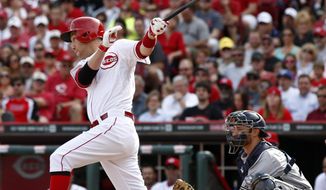 Cincinnati Reds&#x27; Todd Frazier, left, hits a sacrifice fly off Milwaukee Brewers starting pitcher Kyle Lohse scoring Brandon Phillips during the fourth inning of a baseball game, Sunday, May 4, 2014, in Cincinnati. Brewers catcher Jonathan Lucroy watches at right.  (AP Photo/David Kohl)