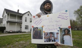In this Saturday, May 3, 2014 photo, Manuel Walker holds up a poster of his mother, Gloria, in the neighborhood where she went missing in 2007 in Cleveland. Gloria lived in the second floor apartment on the left. What hasn’t changed since the stunning discovery of the three women held captive by Ariel Castro is that others are still missing from the same streets. The list of missing people in Cleveland makes up about one out of every 10 cases in the entire state. (AP Photo/Tony Dejak)