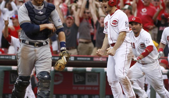 Cincinnati Reds&#x27; Chris Heisey (28) reacts after scoring at home plate on a Todd Frazier double hit off Milwaukee Brewers relief pitcher Tyler Thornburg in the tenth inning of a baseball game on Sunday, May 4, 2014, in Cincinnati. Brewers catcher Jonathan Lucroy, left, walks off the field. The Reds won 4-3. (AP Photo/David Kohl)