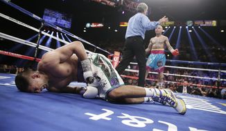 England&#x27;s Amir Khan, left, crumbles to the mat after receiving a low blow from Luis Collazo, right, in their silver welterweight title boxing fight Saturday, May 3, 2014, in Las Vegas. Referee Vic Drakulich is at center. Khan went on to win by unanimous decision. (AP Photo/Isaac Brekken)