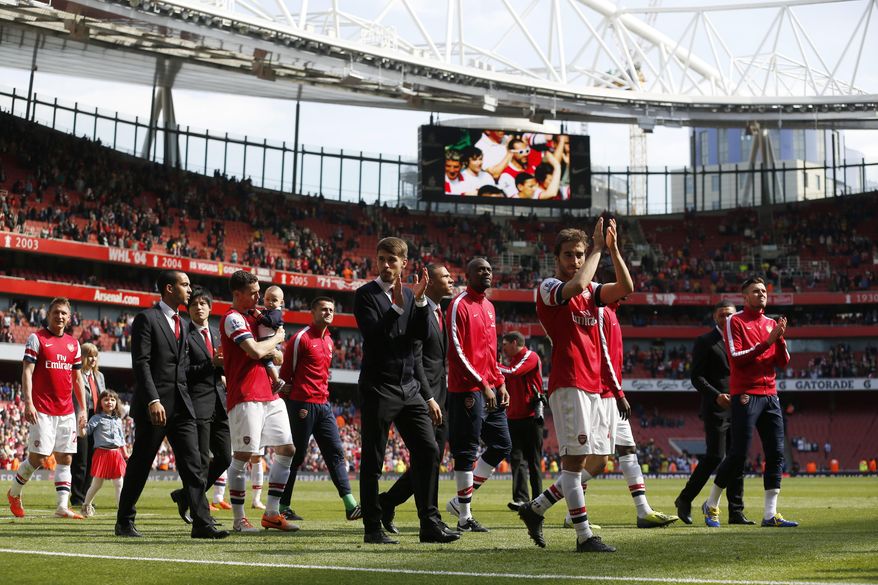 Arsenal's players applaud the supporters as the team parade around the stadium in their last home match of the season at the end of their English Premier League soccer match against West Bromwich Albion at Emirates Stadium in London, Sunday, May 4, 2014. (AP Photo/Sang Tan)