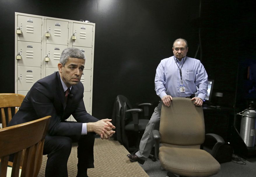 In this Feb. 27, 2014 photo, Julian Ramirez, left, chief of the civil rights division with the Harris County district attorney, and investigator Kirk Bonsal discuss the merits of a shooting simulator used to teach grand jurors about the use of deadly force, in Houston. The simulator projects on a screen various scenarios, including a confrontation with a carjacker, where grand jurors use a specially modified gun and have to decide whether to fire in self-defense. But critics argue that it puts grand jurors in a pro-law enforcement mindset. One Houston defense attorney recently unsuccessfully challenged the simulator’s use, calling it mind manipulation. (AP Photo/Pat Sullivan)