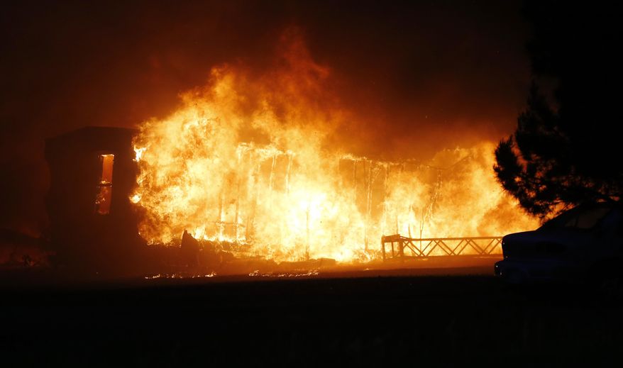 A mobile home burns at a mobile home park near Prairie Grove and Douglas during Oklahoma wildfires in south Logan County, Sunday, May 4, 2014. Firefighters worked through the night and into early Monday to battle the large wildfire that destroyed at least six homes and left at least one person dead after a controlled burn spread out of control in central Oklahoma. (AP Photo/The Oklahoman, Nate Billings) LOCAL STATIONS OUT (KFOR, KOCO, KWTV, KOKH, KAUT OUT); LOCAL WEBSITES OUT; LOCAL PRINT OUT (EDMOND SUN OUT, OKLAHOMA GAZETTE OUT) TABLOIDS OUT