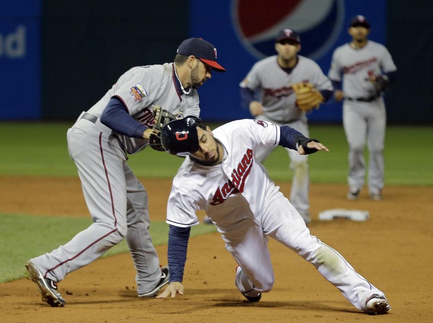 Minnesota Twins right fielder Chris Colabello, left, tags out Cleveland Indians' Mike Aviles on a rundown between first and second in the eighth inning of a baseball game Monday, May 5, 2014, in Cleveland. (AP Photo/Mark Duncan)