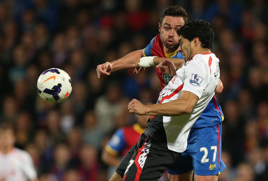 Crystal Palace's Damien Delaney, background,  challenges Liverpool's Luis Suarez during the English Premier League soccer match between Crystal Palace and Liverpool at Selhurst Park stadium in London, Monday, May 5, 2014. (AP Photo/Alastair Grant)