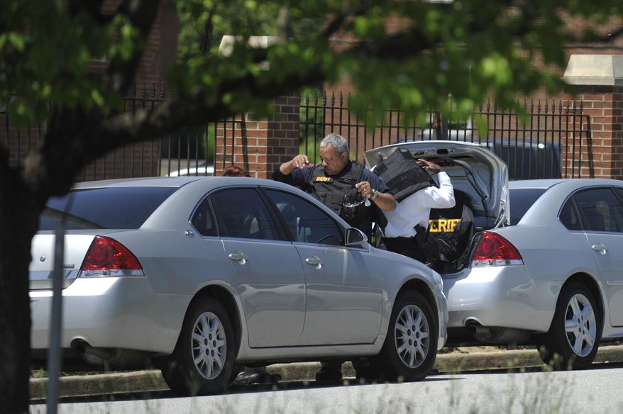 Law enforcement put on kevlar vests before searching the Paine College campus as it is on lockdown on Monday, May 5, 2014, in North Augusta, Ga. The second shooting in two days at a Georgia college Monday left a student with a life-threatening gunshot wound to the head and prompted authorities to pledge to bolster security at the school. (AP Photo/The Augusta Chronicle ,Jon-Michael Sullivan)