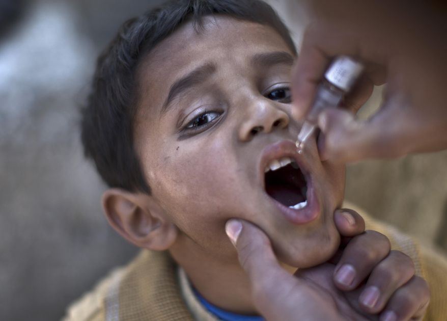 ** FILE ** In this file photo dated Monday Nov. 25, 2013, a Pakistani child is vaccinated against polio by a health worker in Islamabad, Pakistan, Monday, Nov. 25, 2013. (AP Photo/Muhammed Muheisen, FILE)