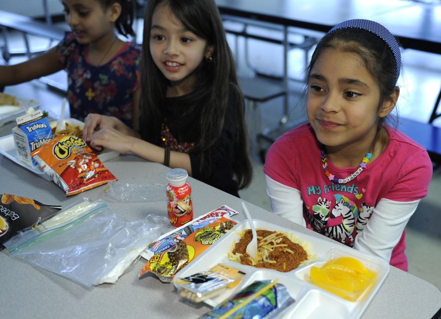 In this Tuesday, April 29, 2014 photo, Brianna Delcid-Gomez, 7, right, Ruth Gebregiorgis, 8, far left, and Amina Sharif, 7, center, eat lunch at the Patrick Henry Elementary School in Alexandria, Va. Starting next school year, pasta and other grain products in schools will have to be whole-grain rich, or more than half whole grain. The requirement is part of a government effort to make school lunches and breakfasts healthier. (AP Photo/Susan Walsh)