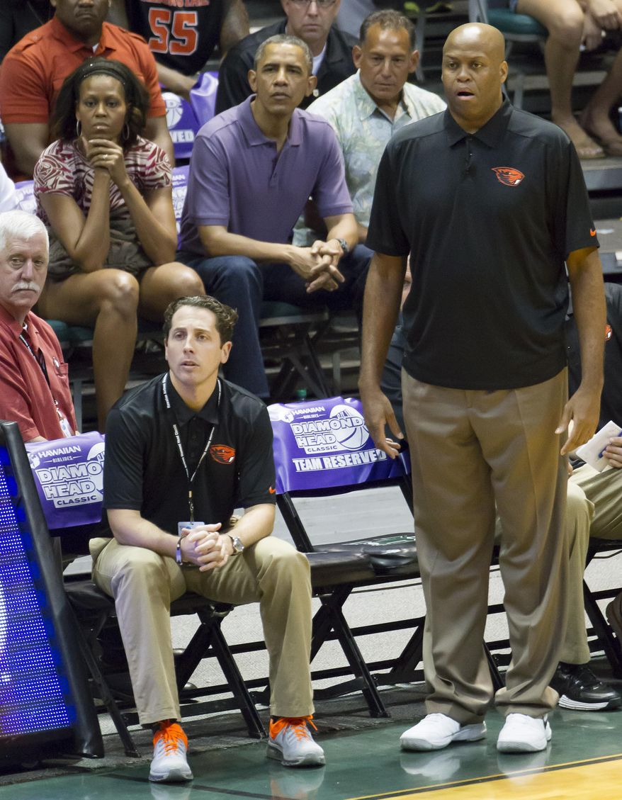 FILE - In this Dec. 22, 2013 file photo, Oregon State head coach Craig Robinson, right, watches his team play Akron along with his brother-in-law President Barack Obama, top center, and his sister the first lady Michelle Obama, top left, in the first half of an NCAA college basketball game at the Diamond Head Classic, in Honolulu. Oregon State fired Robinson, Monday, May 5, 2014, after six seasons without making the NCAA tournament. (AP Photo/Eugene Tanner, File)
