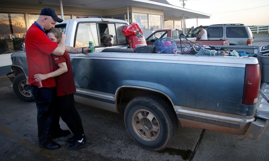 Alyssa Hutton and Jesse Cannon embrace in front of their truck with items they were able to gather before evacuating from a wildfire zone in Logan County, Okla., Sunday, May 4, 2014. About 1,000 people were evacuated from homes in the city about 35 miles north of Oklahoma City Sunday, according to the Guthrie Fire Department. Firefighters worked through the night and into early Monday to battle the large wildfire that destroyed at least six homes and left at least one person dead after a controlled burn spread out of control in central Oklahoma. (AP Photo/The Oklahoman, Sarah Phipps) LOCAL STATIONS OUT (KFOR, KOCO, KWTV, KOKH, KAUT OUT); LOCAL WEBSITES OUT; LOCAL PRINT OUT (EDMOND SUN OUT, OKLAHOMA GAZETTE OUT) TABLOIDS OUT (ONLN OUT; IONLN OUT - MBI)