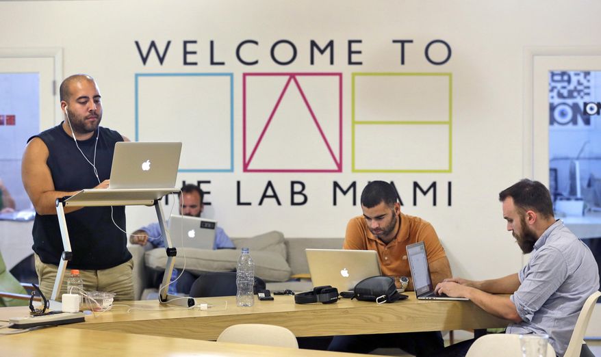 In this Thursday, April 10, 2014 photo, members work at The LAB Miami, a new tech focused collaborative space in the Wynwood Arts District of Miami. Famed for its beaches, cruises and cafecitos, South Florida is now angling to become one of the nation’s next tech hot spots by leveraging its role as the gateway to Latin America and luring northern entrepreneurs with cheap living costs and lots of sun. (AP Photo/Wilfredo Lee)