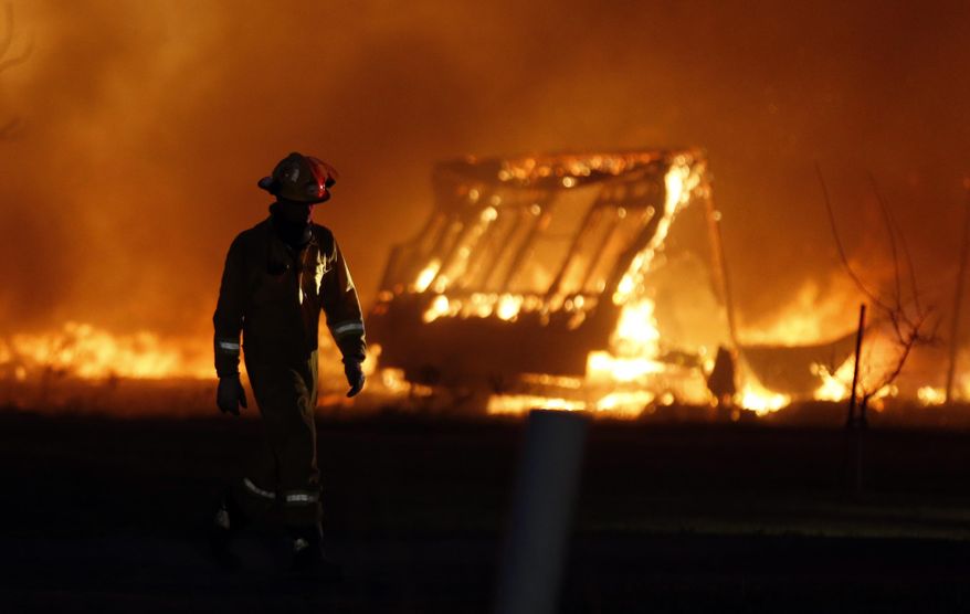 A firefighter walks past a burning mobile home at a mobile home park near Prairie Grove Rd. and Douglas during Oklahoma wildfires in south Logan County, Sunday, May 4, 2014. Firefighters worked through the night and into early Monday to battle a large wildfire that destroyed at least six homes and left at least one person dead after a controlled burn spread out of control in central Oklahoma. (AP Photo/The Oklahoman, Nate Billings) LOCAL STATIONS OUT (KFOR, KOCO, KWTV, KOKH, KAUT OUT); LOCAL WEBSITES OUT; LOCAL PRINT OUT (EDMOND SUN OUT, OKLAHOMA GAZETTE OUT) TABLOIDS OUT