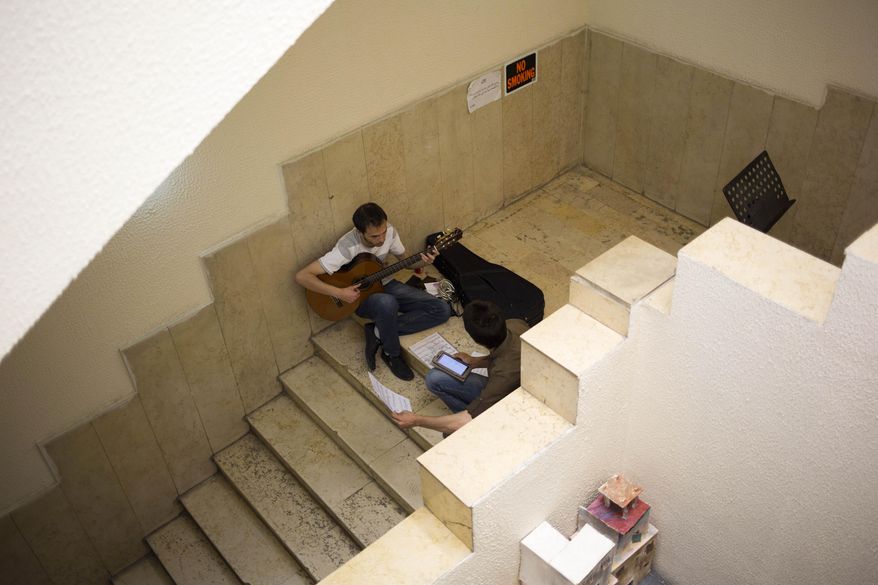 In this Sunday, May 4, 2014 photo, a student plays guitar during a break at an art school which adjoins the Damascus Opera House in Damascus, Syria. Two students were killed and five others were wounded when a mortar landed outside the Opera building in April 2014. (AP Photo/Dusan Vranic)