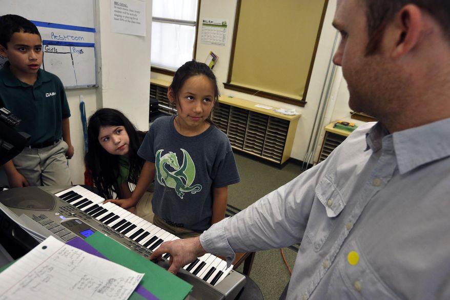 In this April 22, 2014 photo, students listen to a visiting outside instructor during music class, at Cole Elementary, in Denver. Colorado lawmakers were poised to finish work Tuesday, May 6 on one of the heftiest (and most lobbied) measures of the term: a half-billion Dollar education spending plan aimed at backfilling public schools harmed by years of recession-era budget cuts. (AP Photo/Brennan Linsley)