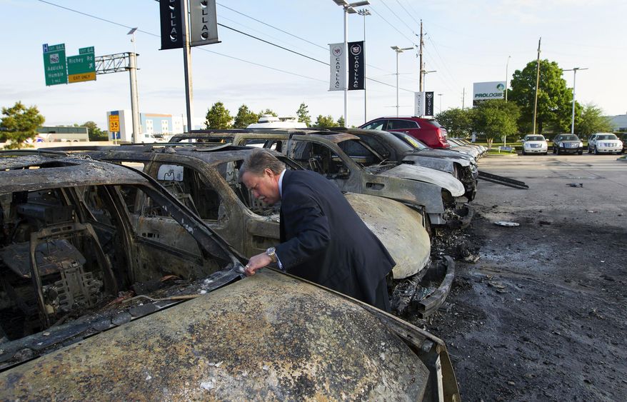 General Manager Steven Hainline walks near a row of burnt Cadillac Escalades at Tom Peacock Cadillac Tuesday, May 6, 2014, in Houston. The vehicles burned to the ground after a wreck sparked a fire igniting the Escalades on the lot. General Manager Steven Hainline said the damage totals nearly $750,000. (AP Photo/Houston Chronicle, Cody Duty)
