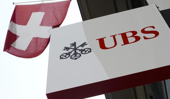 FILE - The April 24, 2014 file photo shows the logo of Swiss bank UBS and the Swiss flag in Zurich, Switzerland. Solid returns from its wealth management and investment banking divisions helped Switzerland&#x27;s biggest bank, UBS AG, post a 7 percent profit advance in the first quarter.  (AP Photo/Keystone, Steffen Schmidt)