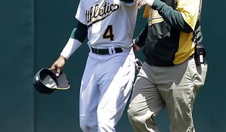 Oakland Athletics&#39; Coco Crisp, left, holds his neck as he walks off the field with head trainer Nick Paparesta in the third inning of a baseball game Wednesday, May 7, 2014, in Oakland, Calif. Crisp injured himself after hitting the wall while catching a ball hit by Seattle Mariners&#39; Kyle Seager. (AP Photo/Ben Margot)
