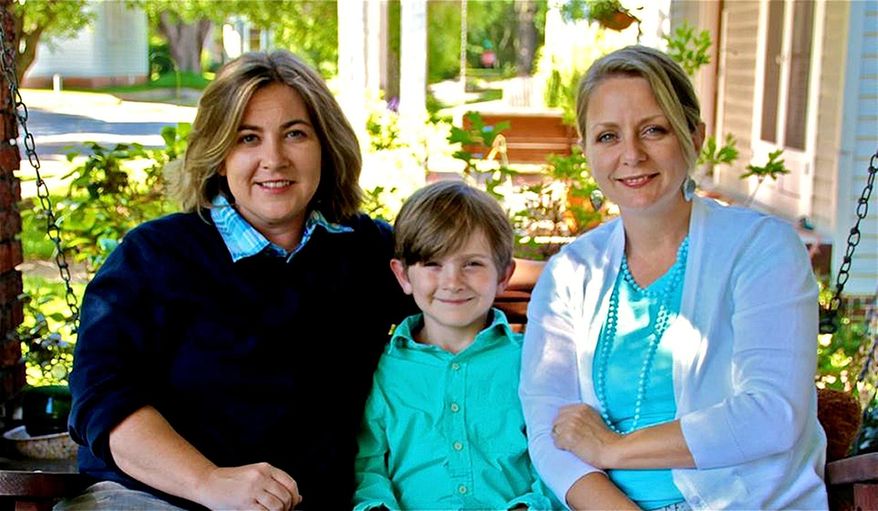 This undated photo provided by Cari Searcy, Searcy sits with partner Kimberly McKean, right, and their 8-year-old son Khaya at their home in Mobile, Ala. Searcy and McKean filed a federal lawsuit Wednesday seeking to force the state to recognize their out-of-state marriage so they can both be legal parents to their 8-year-old son. The suit contends that Alabama's ban on same-sex marriage and refusal to recognize such marriages from other states violates the equal protection clause of the U.S. Constitution. (AP Photo/Courtesy of Cari Searcy)