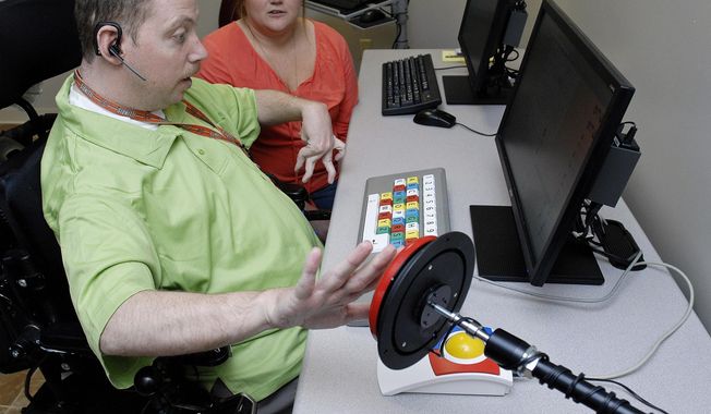 In this April 21, 2014 photo, Robby Stephens uses a modified keyboard as Rebecca Ostler, director of developmental training at the office of Marcfirst looks on in Normal, Ill. Stephens, for the first time, was using the new adaptive computer lab by Marcfirst for people with intellectual and developmental disabilities. Individuals will use the lab to improve their typing skills, present their individualized service plans to staff, search the Internet and participate in presentations, said Ostler. (AP Photo/The Pantagraph, Lori Ann Cook-Neisler)