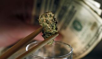 **FILE** A caregiver picks out a marijuana bud for a patient at a marijuana dispensary in Denver on Sept. 18, 2012. (Associated Press)