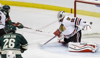 Minnesota Wild left wing Erik Haula, top left, of Finland, scores on Chicago Blackhawks goalie Corey Crawford (50) during the third period of Game 3 of an NHL hockey second-round playoff series in St. Paul, Minn., Tuesday, May 6, 2014. The Wild won 4-0. (AP Photo/Ann Heisenfelt)