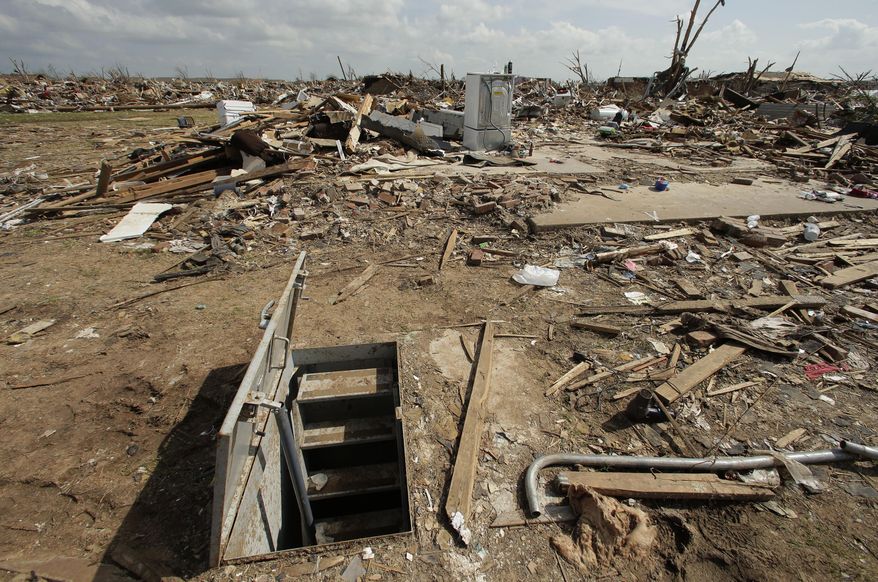 FILE - In this May 26, 2013, file photo, an underground shelter is seen near tornado rubble in Moore, Okla. The deadly tornadoes that killed more than 30 people scared Oklahomans in a way that previous storms had not, moving them to add tornado shelters or reinforced safe rooms to their homes. But the surge of interest in tornado safety has overwhelmed companies that build the shelters. Now there are long waiting lists, and many people have to endure the most dangerous part of the season with no added protection. (AP Photo/Charlie Riedel, File)