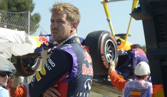 Red Bull driver Sebastian Vettel of Germany looks around as his car is taken away after he lost control  during a first free practice session at the Barcelona Catalunya racetrack in Montmelo, near Barcelona, Spain, Friday, May 9, 2014. The Formula One race will be held on Sunday. (AP Photo/Manu Fernandez)
