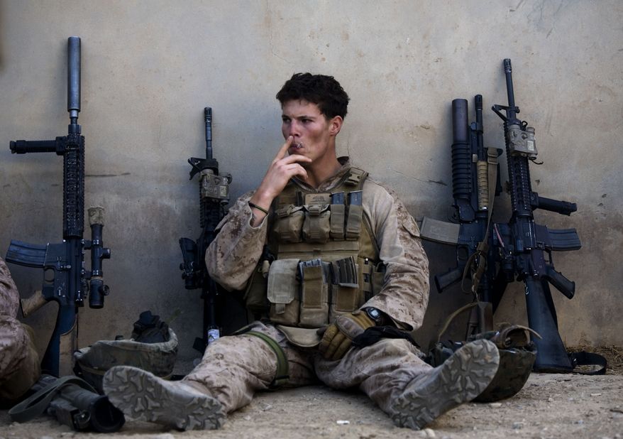 Cpl. Kevin Frame, of Woodlake, California, with India company, 3rd Battalion 5th Marines, First Marine Division, smokes during a break in patrol, Wednesday, Nov. 3, 2011, in Sangin, south of Kabul, Afghanistan. (AP Photo/Dusan Vranic)