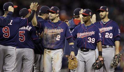 Minnesota Twins second baseman Brian Dozier (2), shortstop Danny Santana (39) and right fielder Chris Colabello (20) celebrate their 2-1 win over the Detroit Tigers with teammates after a baseball game in Detroit, Friday, May 9, 2014. (AP Photo/Carlos Osorio)