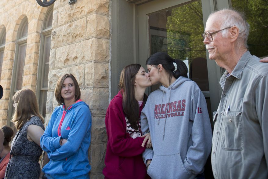 Jennifer Rambo, left, of Jacksonville, Ark., kisses her partner Kristin Seaton, right, of Fort Smith, Ark., as they wait in line at the Carroll County Courthouse to apply for a marriage license, Saturday, May 10, 2014, in Eureka Springs, Ark. Rambo and Seaton drove to Eureka Springs Friday night and slept in their car after a judge overturned Ammendment 83, which banned same-sex marriage in the state of Arkansas. (AP Photo/Sarah Bentham)