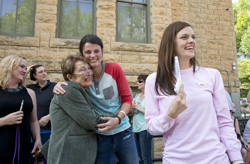 Jennifer Rambo, right, smiles as her partner Kristin Seaton, center, hugs Sheryl Maples, left, the lead attorney who filed the Wright v. the State of Arkansas lawsuit, Saturday, May 10, 2014, in Eureka Springs, Ark. A judge overturned amendment 83 Friday, which banned same-sex marriage in the state of Arkansas. (AP Photo/Sarah Bentham)
