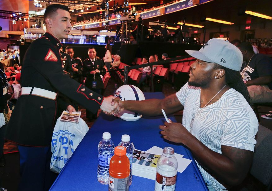 New York Jets running back Chris Ivory, right, greets Lance Cpl. Julio Ortiz while signing autographs for fans during the fourth round of the 2014 NFL Draft, Saturday, May 10, 2014, in New York. (AP Photo/Julie Jacobson)