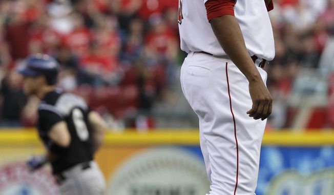 Cincinnati Reds starting pitcher Alfredo Simon, right, stands on the mound after giving up a home run to Colorado Rockies&#x27; Corey Dickerson (6) in the first inning of a baseball game on Saturday, May 10, 2014, in Cincinnati. (AP Photo/Al Behrman)
