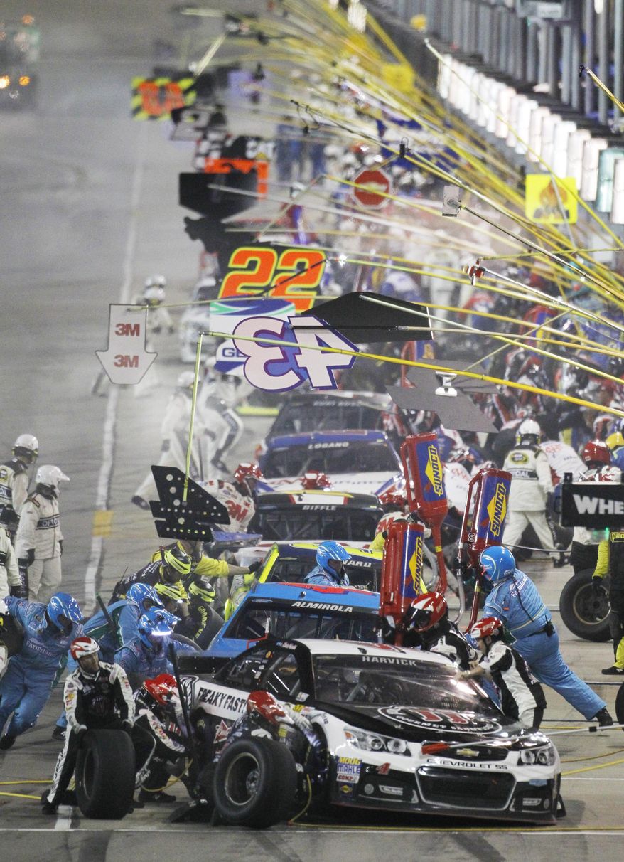 NASCAR driver Kevin Harvick (4) heads the line of teams making a pit stop during the Sprint Cup Series auto race at Kansas Speedway in Kansas City, Kan., Saturday, May 10, 2014. (AP Photo/Colin E. Braley)