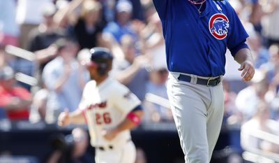 Chicago Cubs relief pitcher James Russell, right,wipes his face as Atlanta Braves' Dan Uggla (26) rounds third base to score on a Jason Heyward home run in the seventh inning of a baseball game on Sunday, May 11, 2014, in Atlanta. (AP Photo/John Bazemore)