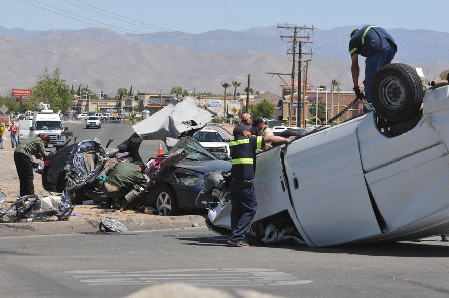Authorities work on the scene of a fatal traffic accident in Hesperia, Calif, Sunday, May 11, 2014. A spokeswoman with the San Bernardino County Sheriff's Department says that four people are confirmed dead after a van smashed into a car that was sitting at a stop sign. (AP Photo/The Victor Valley Daily Press, David Pardo)