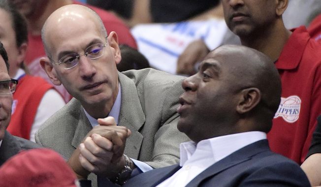NBA Commissioner Adam Silver, left, shakes hands with Magic Johnson as they watch the Los Angeles Clippers play the Oklahoma City Thunder in the first half of Game 4 of the Western Conference semifinal NBA basketball playoff series, Sunday, May 11, 2014, in Los Angeles. (AP Photo/Mark J. Terrill)