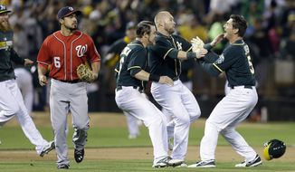 Oakland Athletics&#39; John Jaso, right, celebrates after making the game-winning hit against the Washington Nationals in the 10th inning of a baseball game Saturday, May 10, 2014, in Oakland, Calif. At left is Nationals&#39; Anthony Rendon (6). (AP Photo/Ben Margot)