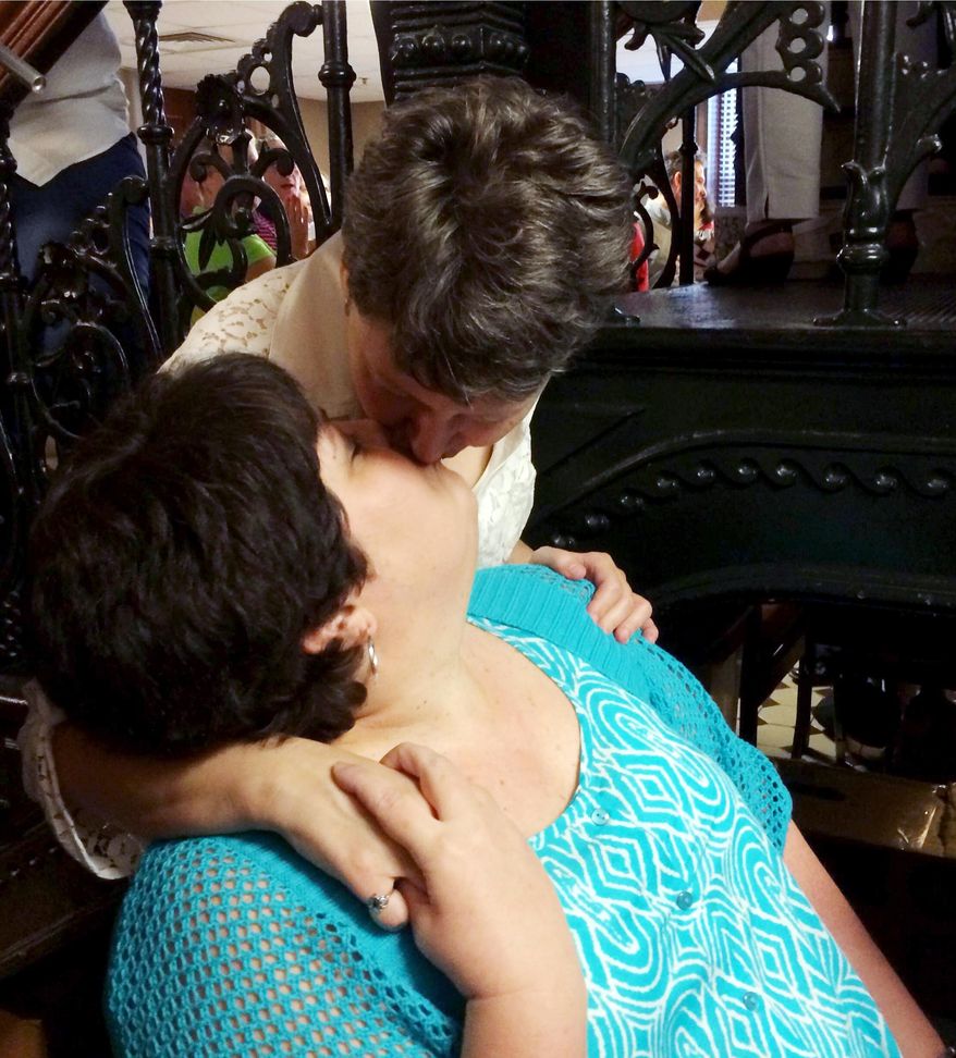 Susan Farr, left, and Shelly Butler, both of Dallas, who were first to file paperwork for a marriage license at the Pulaski County Courthouse in Little Rock, Ark., kiss after their wedding ceremony Monday, May 12, 2014. The state's largest county began issuing gay marriage licenses following a judge's ruling overturning Arkansas' constitutional ban on same-sex marriage. (AP Photo/Christina Huynh)