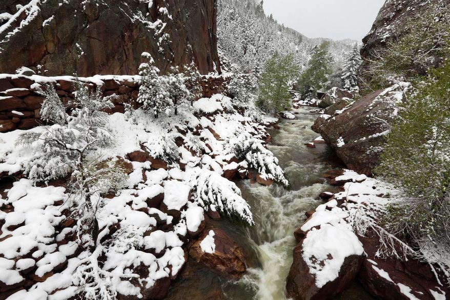 Water flows down a canyon past fresh snow, at Eldorado Canyon State Park, in Eldorado Springs, Colo., on Monday, May 12, 2014. A spring storm has brought up to 3 feet of snow to the Rockies and severe thunderstorms and tornadoes to the Midwest. In Colorado, the snow that began falling on Mother's Day caused some power outages as it weighed down newly greening trees. (AP Photo/Brennan Linsley)