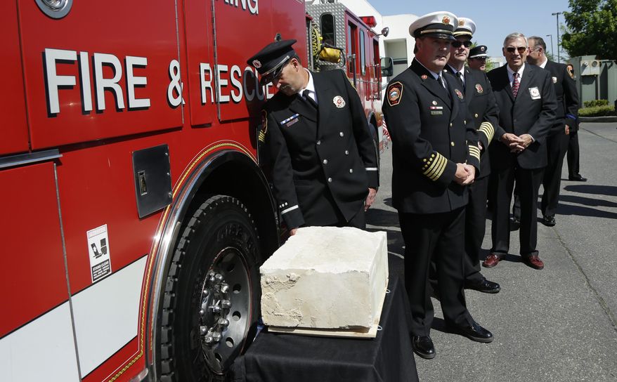 South King Co. Fire and Rescue officials, including assistant chief Gordon Olson, second from left, stand Monday, May 12, 2014, next to a piece of limestone that was part of the building at the Pentagon in Washington, DC, before it was destroyed in the September 11, 2001 terrorist attacks. The stone was delivered during a ceremony at the Alaska Airlines cargo facility in Seatac, Wash., and will be part of a Sept. 11th memorial in Federal Way, Wash. that will be dedicated on Sept. 11, 2014, and also contains a beam from the World Trade Center in New York and a rock from the field in Shanksville, Pa., where United flight 93 crashed during the attacks. (AP Photo)