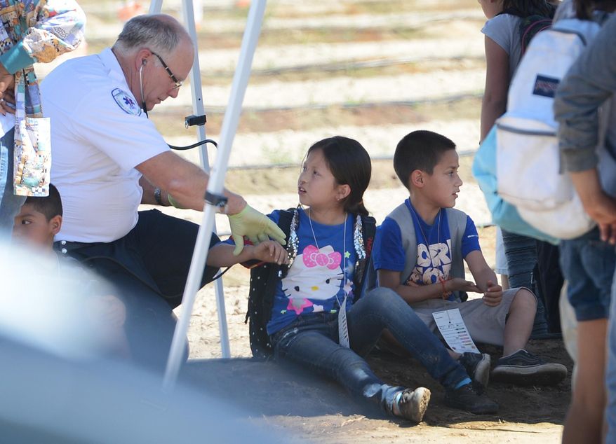 A medic attends to children who had been aboard a school bus that collided with a fuel truck at Central and Elm avenues south of Fresno, Calif., Monday, May 12, 2014. No critical injuries were reported. (AP Photo/The Fresno Bee, Craig Kohlruss)