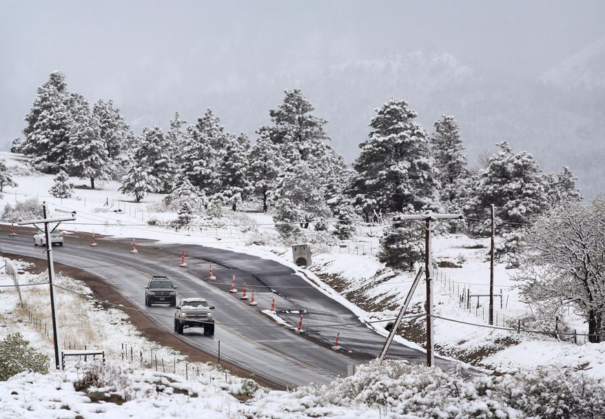 Commuters pass fresh snow from the fringe of a major spring snowstorm in the nearby mountains, in Superior, Colo., on Monday, May 12, 2014. A spring storm has brought up to 3 feet of snow to the Rockies and severe thunderstorms and tornadoes to the Midwest. In Colorado, the snow that began falling on Mother's Day caused some power outages as it weighed down newly greening trees. (AP Photo/Brennan Linsley)