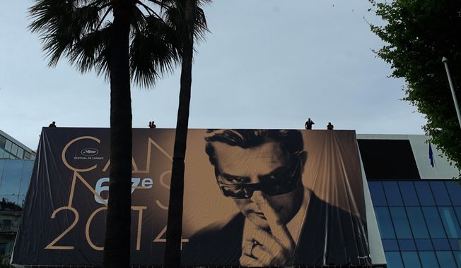 Workers place a banner depicting Marcello Mastroianni from Federico Fellini’s film 8½ on the Palais during preparations for the 67th international film festival, Cannes, southern France, Monday, May 12, 2014. The festival runs from May 14 to May 25. (AP Photo/Thibault Camus)