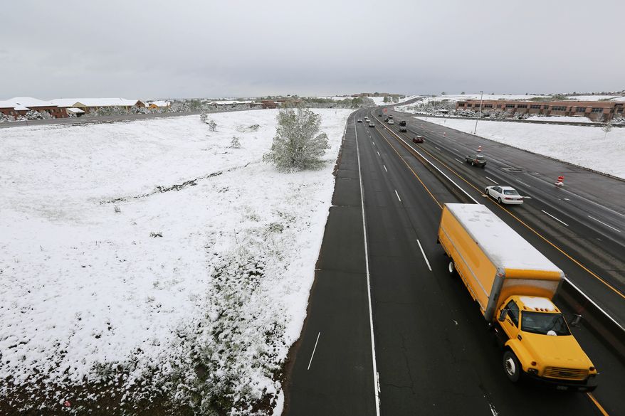 Commuters pass fresh snow from the fringe of a major spring snowstorm in the nearby mountains, in Louisville, Colo., on Monday, May 12, 2014. A spring storm has brought up to 3 feet of snow to the Rockies and severe thunderstorms and tornadoes to the Midwest. In Colorado, the snow that began falling on Mother's Day caused some power outages as it weighed down newly greening trees. (AP Photo/Brennan Linsley)